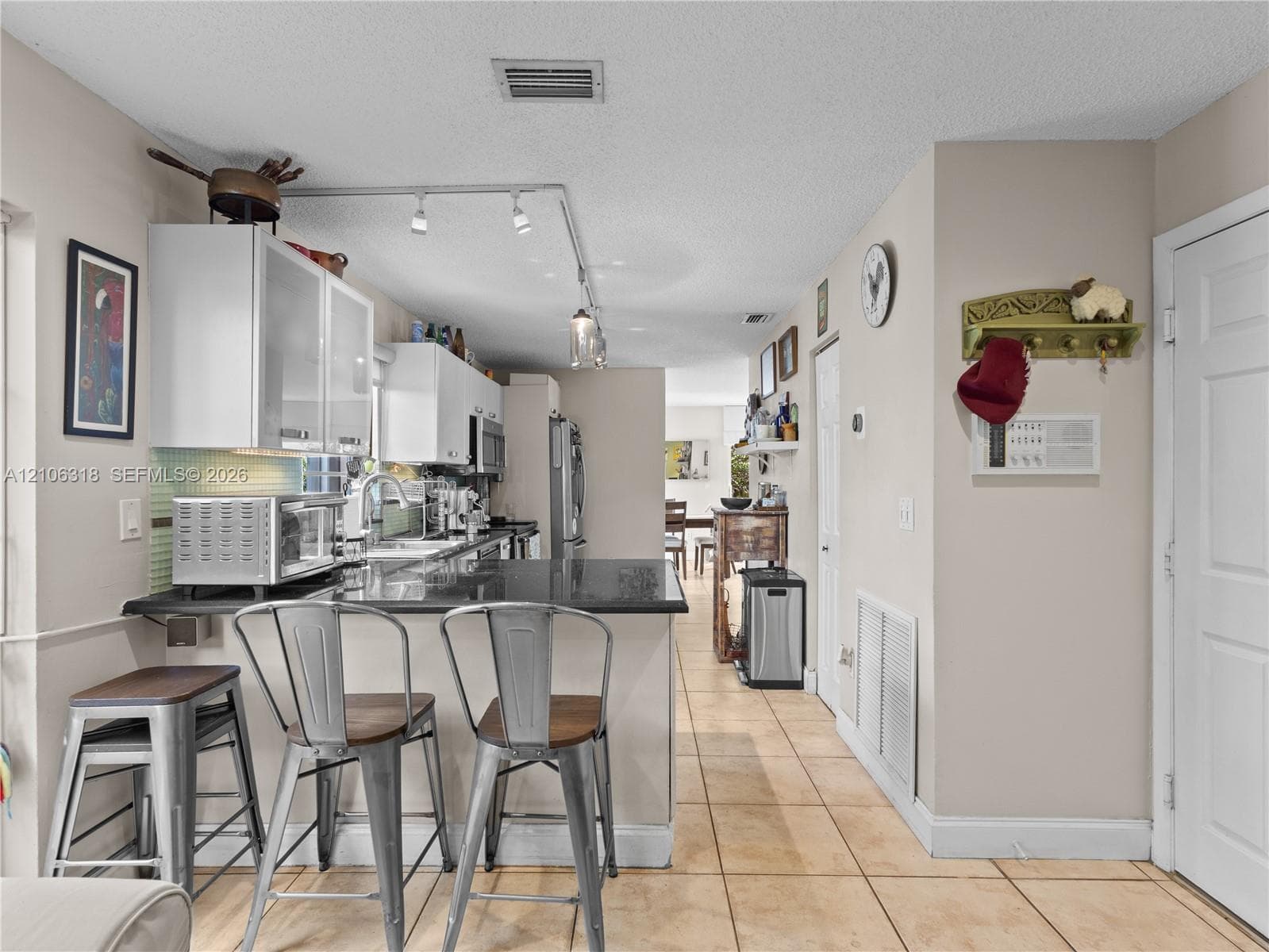 Kitchen featuring white cabinetry with glass-front uppers, solid surface countertops, track lighting, and ceramic tile flooring