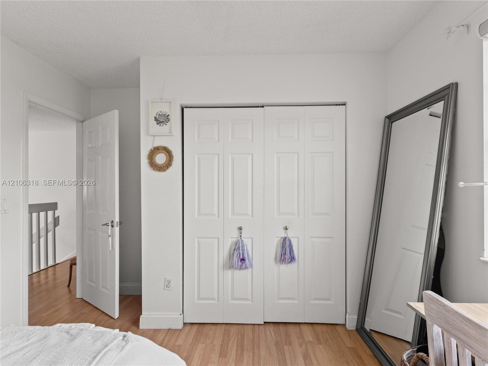 Wood-finish flooring, white six-panel interior doors, and double-door closet with six-panel design