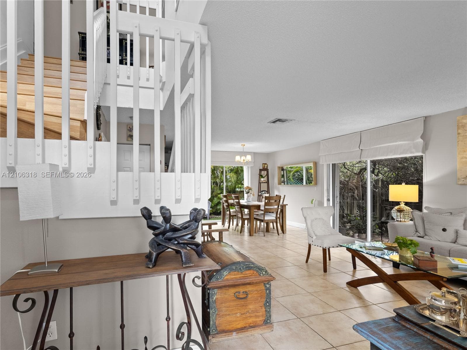 Open-concept interior featuring large-format tile flooring, a staircase with white vertical balusters and wood treads, and sliding glass doors