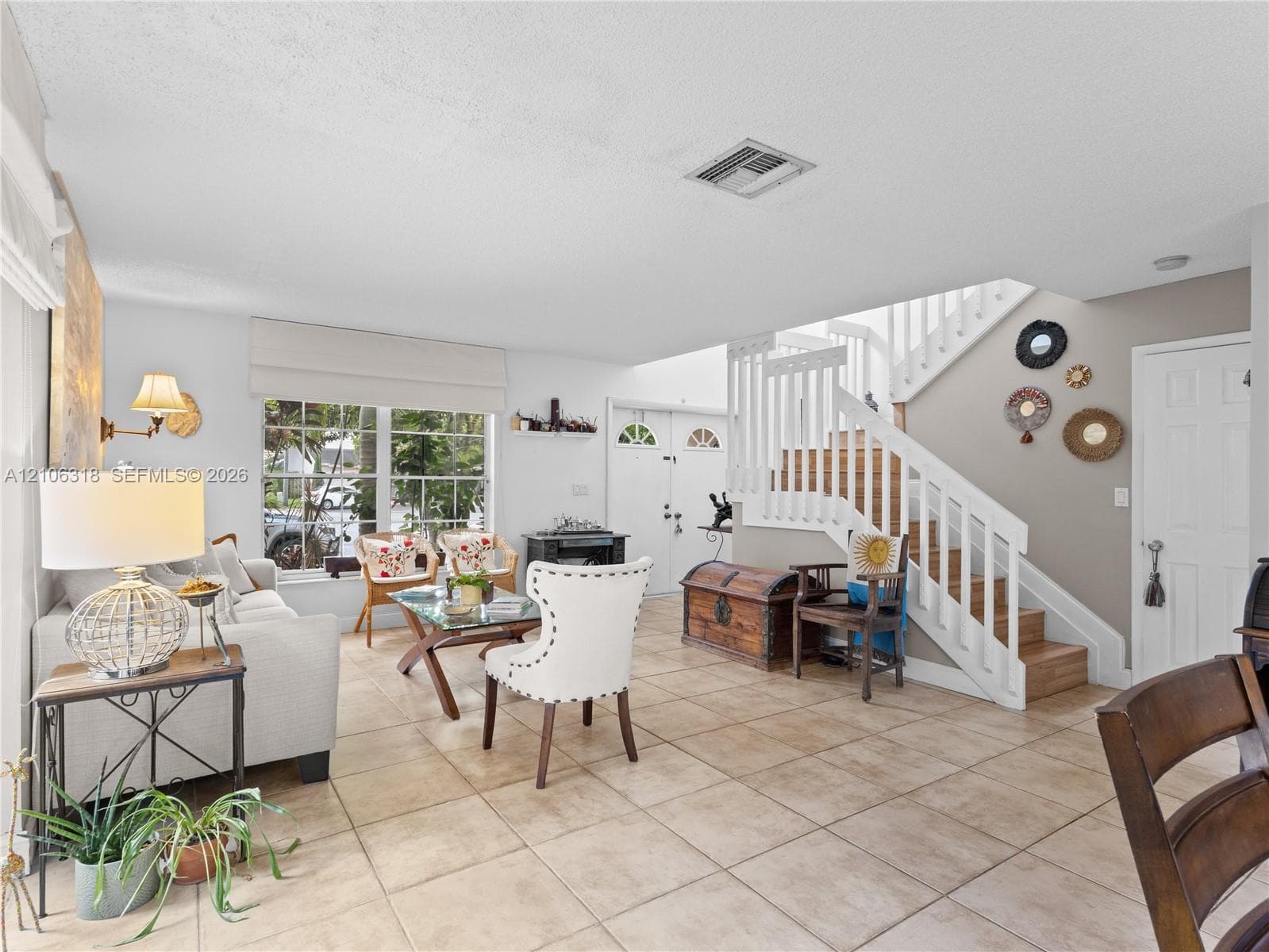 Open-concept living space featuring large-format tile flooring, a multi-pane window with Roman shades