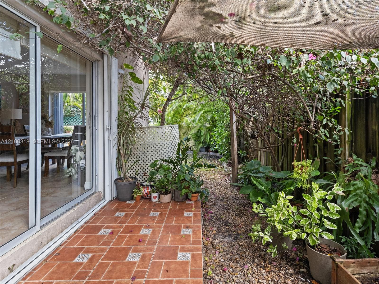 Outdoor patio featuring terracotta-style tile flooring, sliding glass door, and a lattice privacy screen