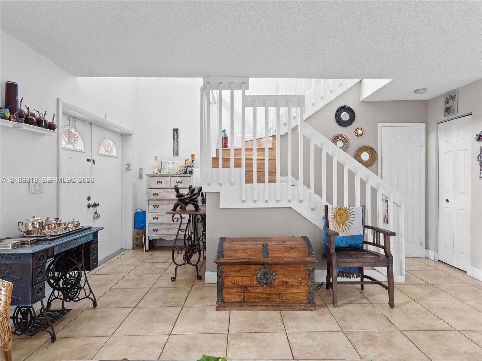 Entryway featuring ceramic tile flooring, a staircase with white balusters and wooden treads, double entry doors with integrated window panes, and interior doors with paneled detailing