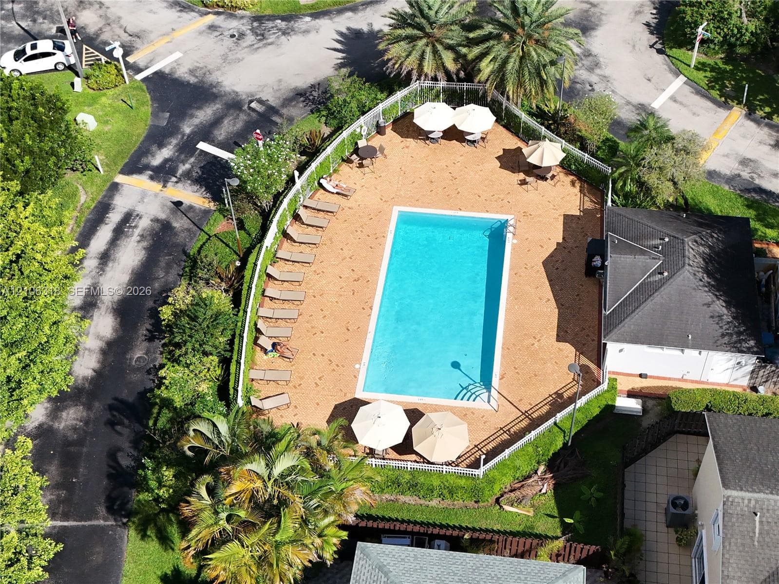 Community swimming pool featuring a rectangular basin, perimeter fencing, and an expansive paved deck