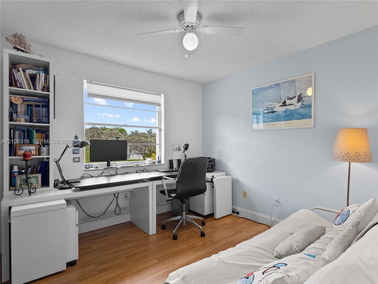 Wood-finish flooring, built-in shelving unit, multi-pane window, and central ceiling fan with integrated light fixture