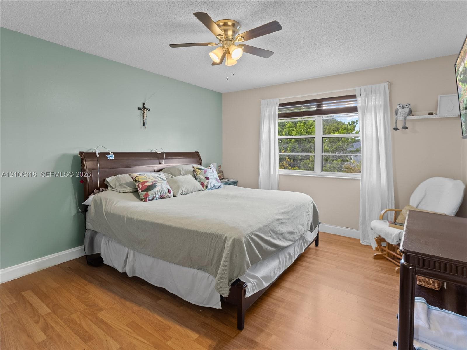 Wood-finish flooring, multi-pane window, and brushed brass-finish ceiling fan with integrated lighting