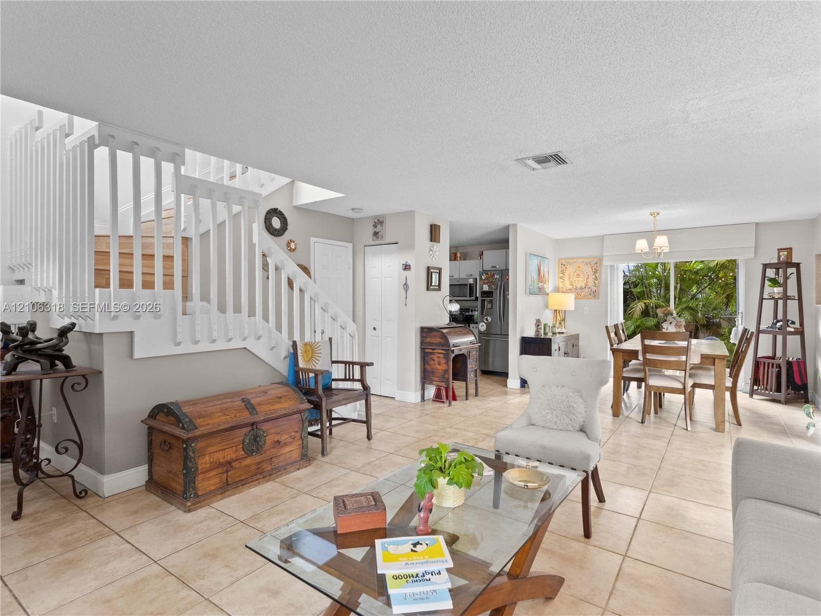 Open-concept interior featuring large-format tile flooring, a staircase with white balusters, and sliding glass doors with exterior access