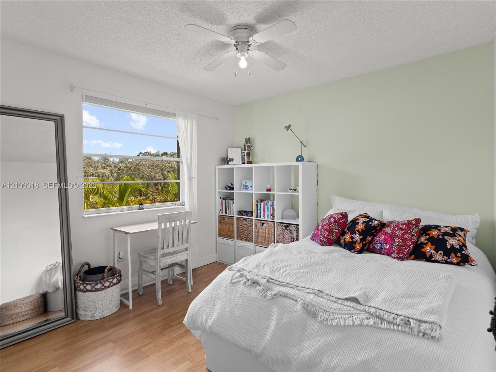 Bedroom featuring wood-finish flooring, a neutral accent wall, and a ceiling-mounted fan with light fixture
