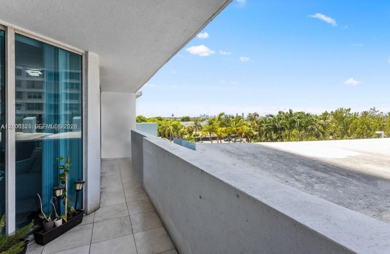 Covered balcony featuring tile flooring, floor-to-ceiling glass paneling, and concrete wall accents