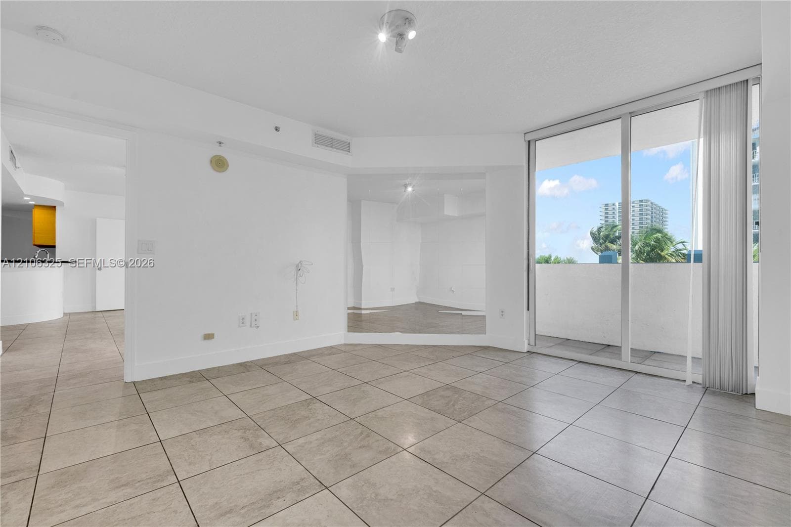 Open-concept interior featuring large-format ceramic tile flooring, floor-to-ceiling glass sliding doors, and a wall-integrated mirror