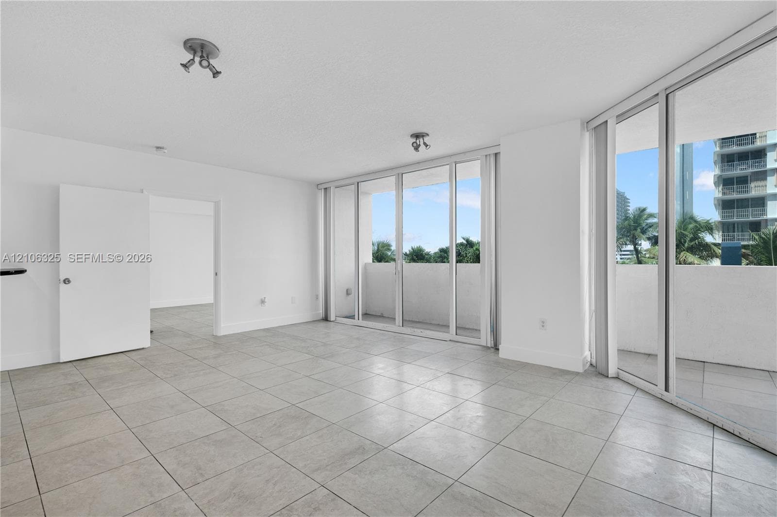 Floor-to-ceiling sliding glass doors, ceramic tile flooring, and integrated balcony access with exterior railings