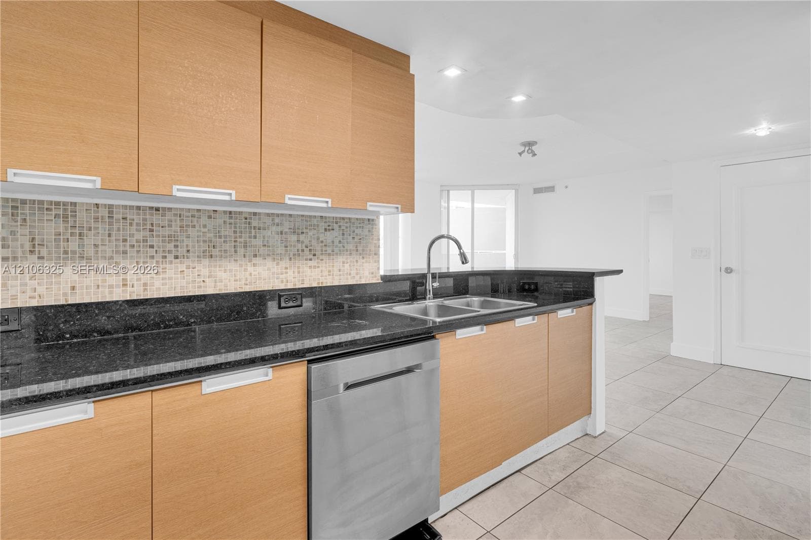 Kitchen featuring flat-panel wood-finish cabinetry, dark stone countertops, a mosaic tile backsplash, stainless steel dishwasher, and a dual-basin stainless steel sink with a gooseneck faucet