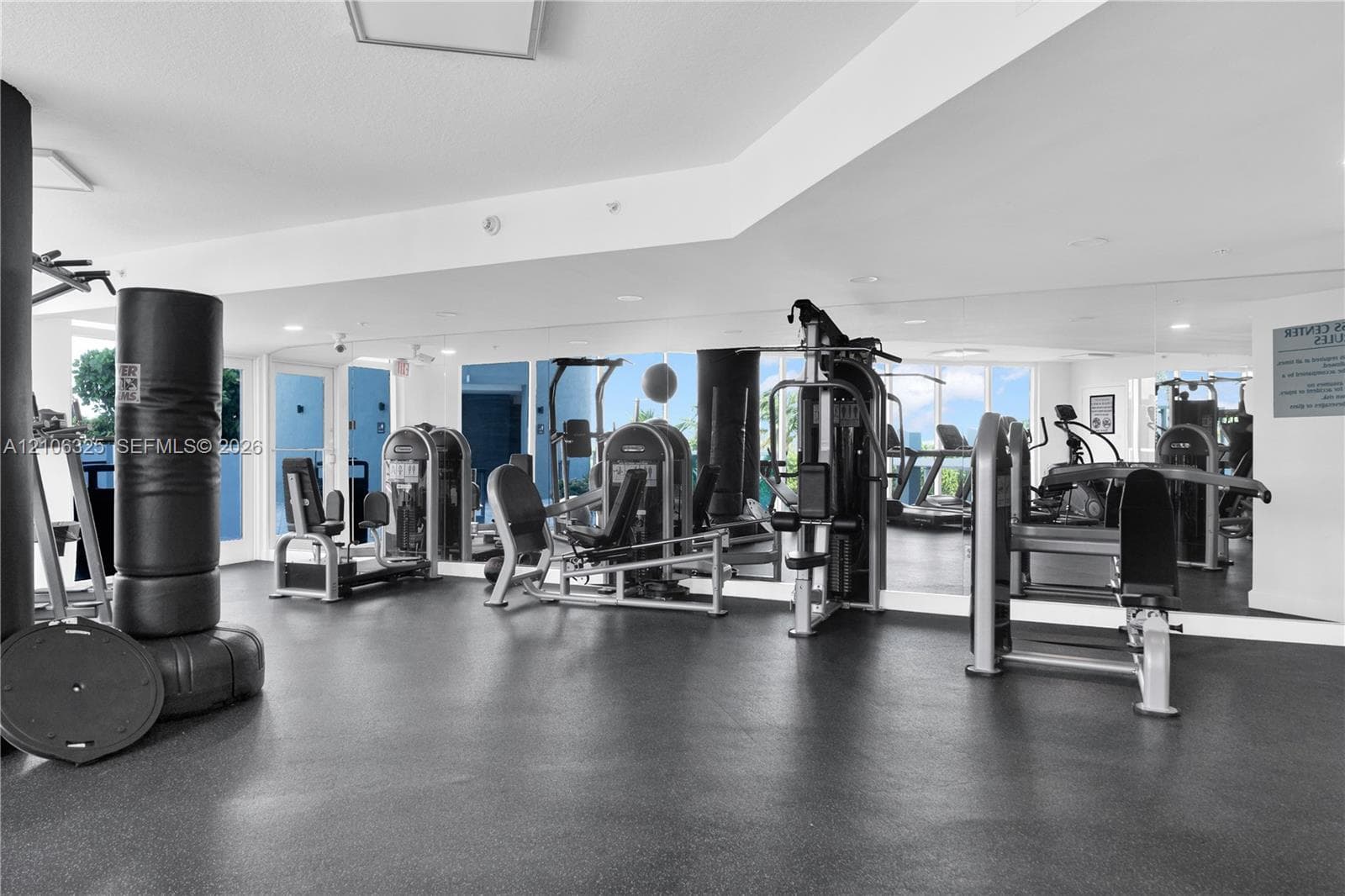 Fitness center featuring rubberized flooring, floor-to-ceiling wall mirrors, and recessed ceiling lighting