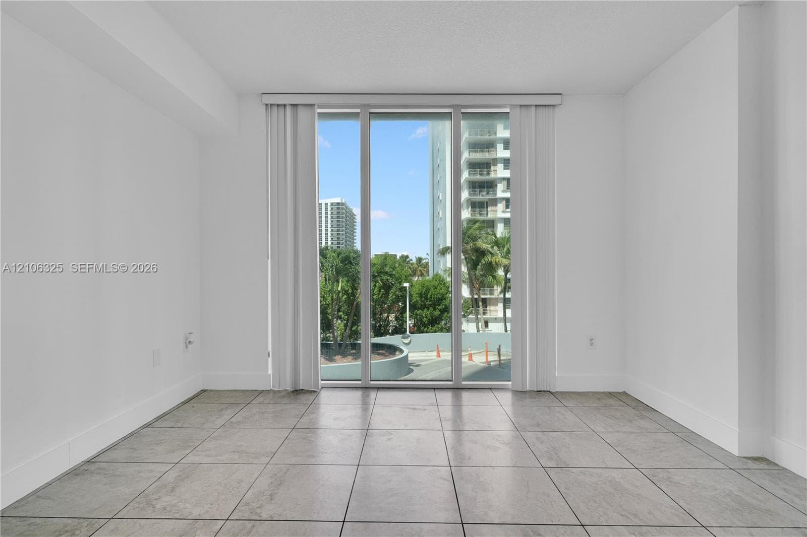Floor-to-ceiling windows featuring neutral-toned tile flooring and white wall finishes