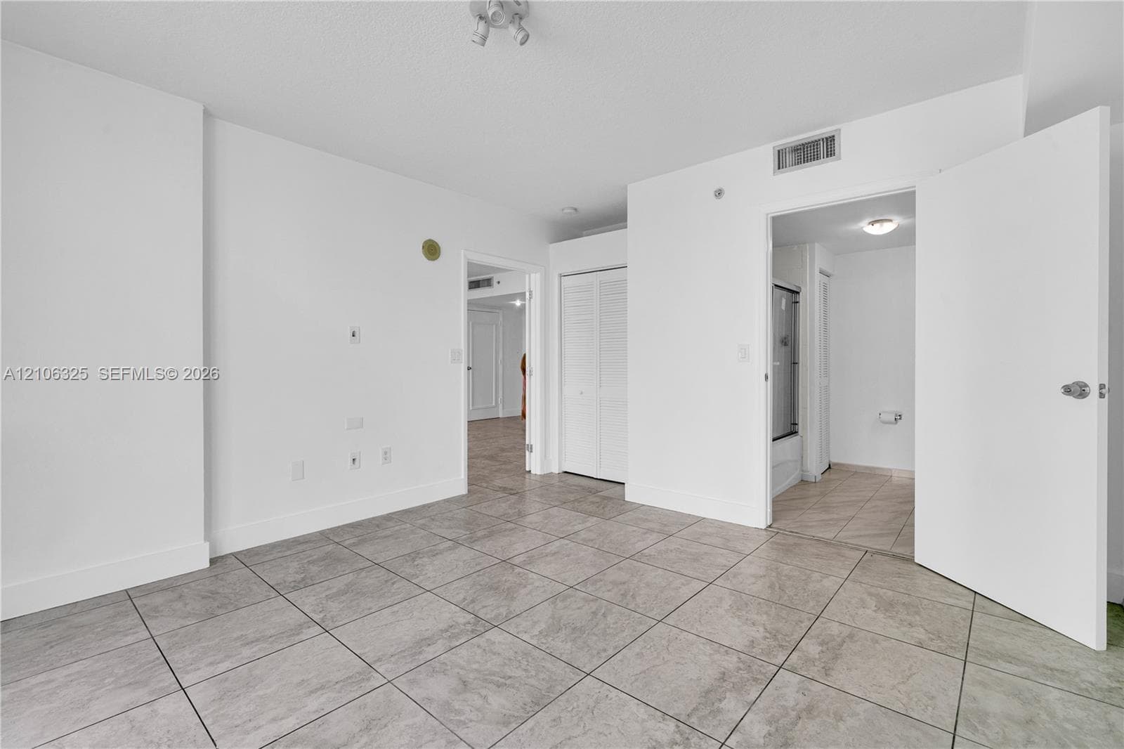 Interior space featuring large-format ceramic tile flooring, neutral wall finishes, multi-panel closet doors, and recessed ceiling lighting