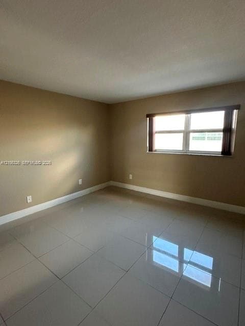 Room featuring large-format polished tile flooring, neutral wall paint, and a horizontal window with a fitted valance