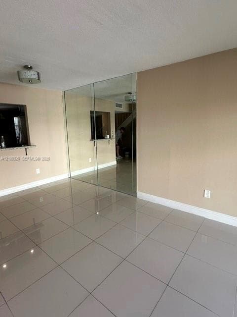 Neutral tile flooring, large floor-to-ceiling mirror panel, pass-through opening with stone-finish ledge, and contemporary drum-style ceiling lighting