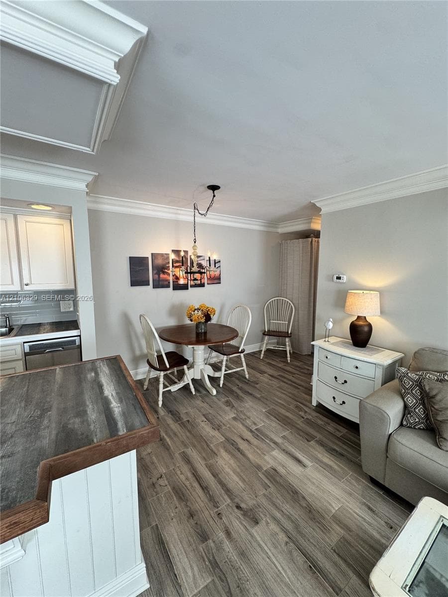 Wood-finish flooring, crown molding, and an elevated kitchen counter featuring a wood-tone surface and vertical paneling