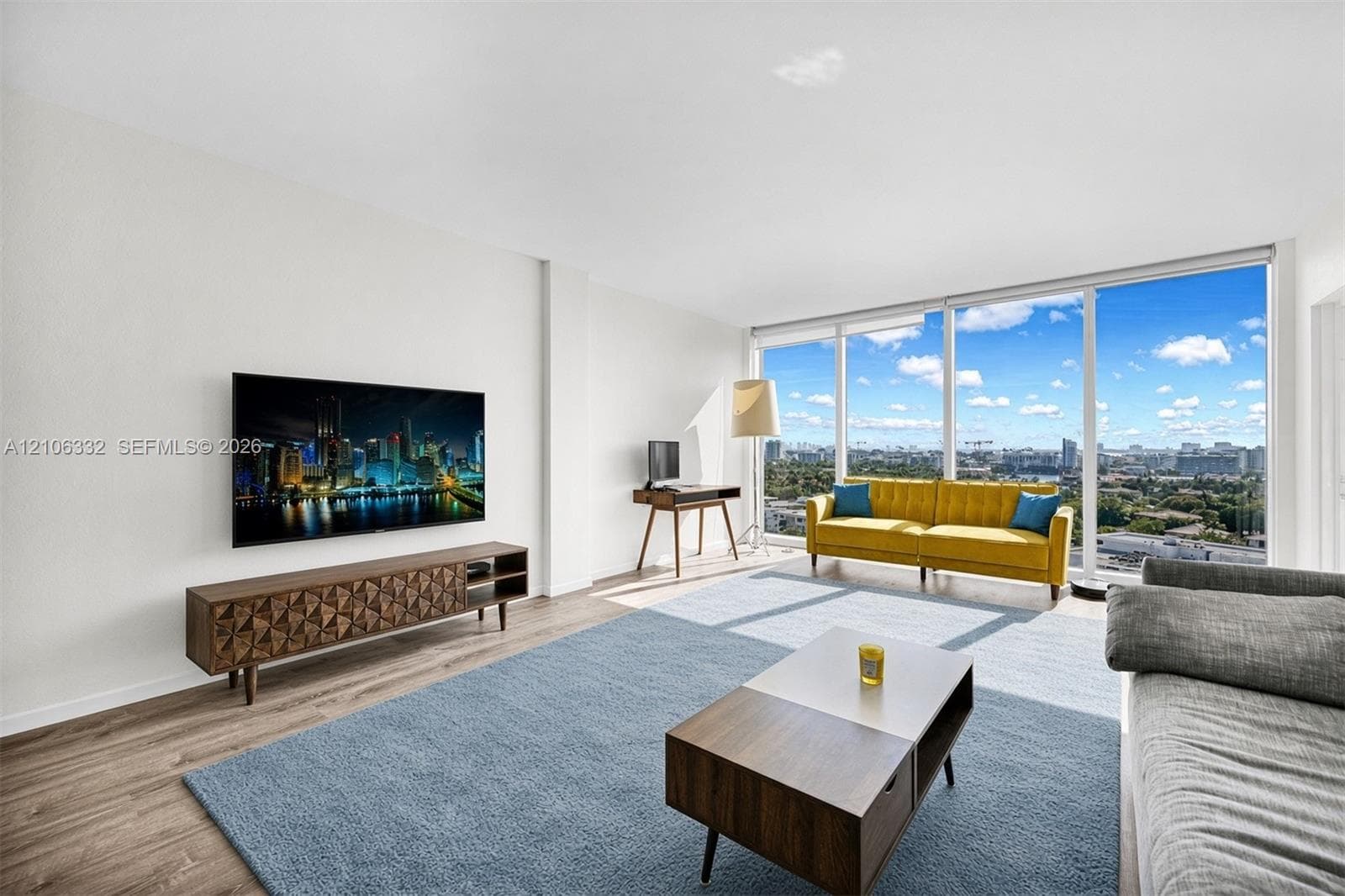 Floor-to-ceiling windows, wood-finish flooring, and expansive urban scenery