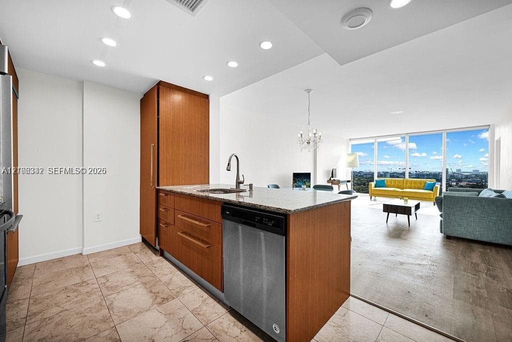 Kitchen featuring wood-finish cabinetry, stone-surface countertops, stainless steel appliances, recessed lighting, and tile flooring