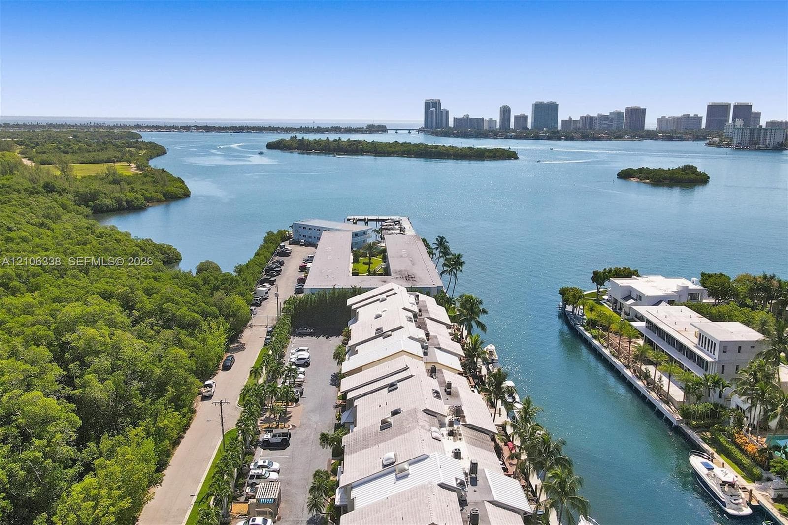 Aerial perspective of waterfront property featuring a deep-water boat slip, direct access to the bay, and palm-lined grounds