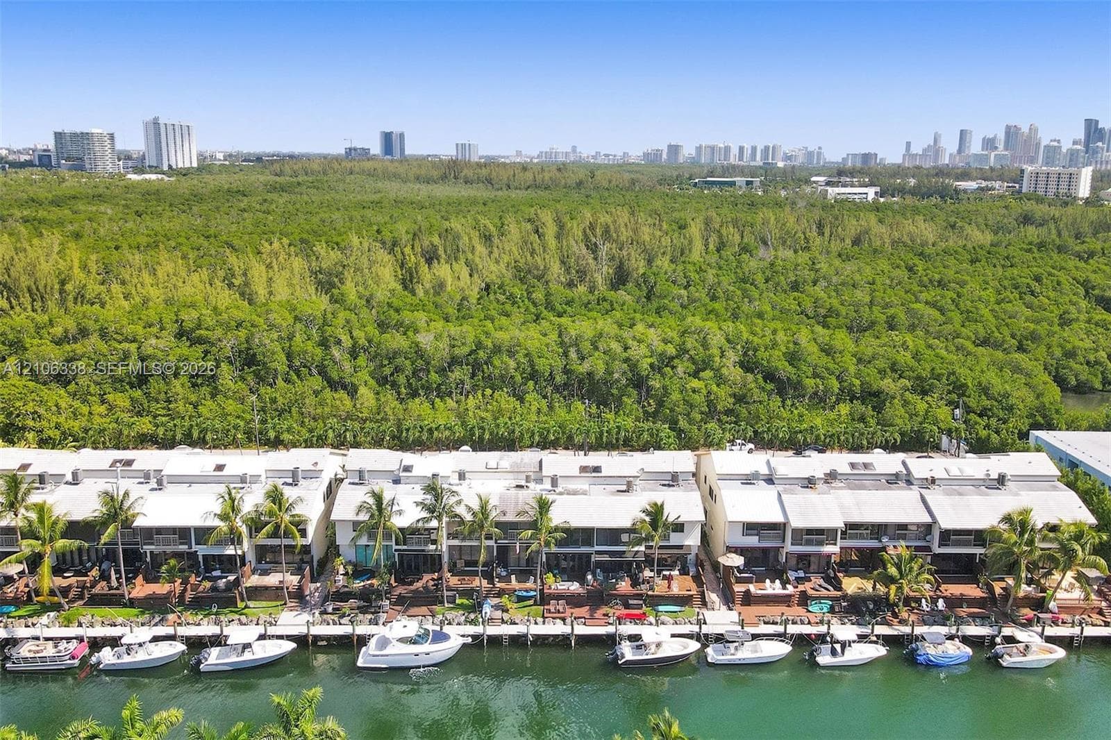 Waterfront townhome community featuring private boat slips, rear decks, concrete seawall, and mature palm landscaping with proximity to urban skyline and preserve areas