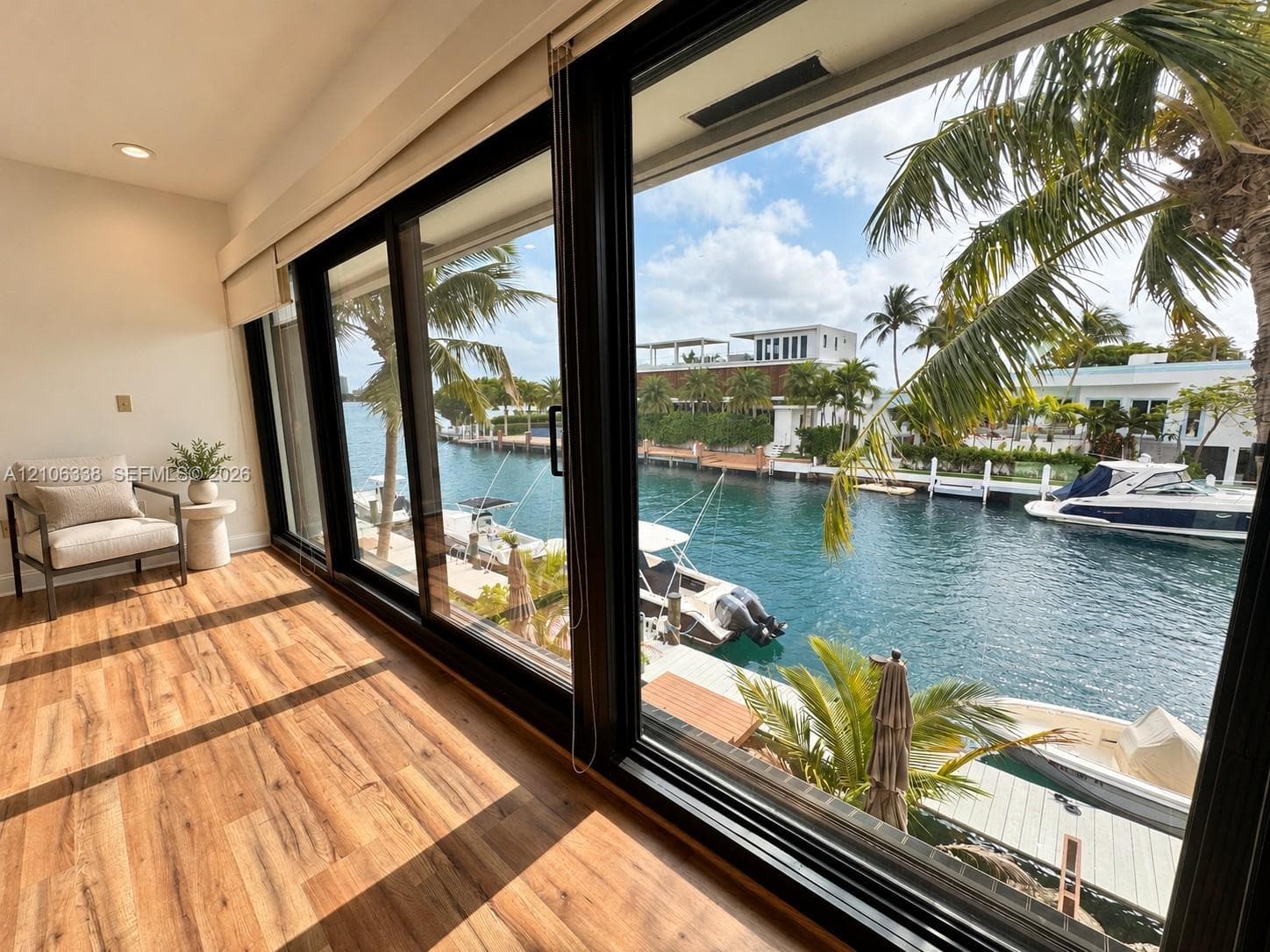 Floor-to-ceiling sliding glass doors, wood-finish flooring, recessed lighting, and water frontage with private docking