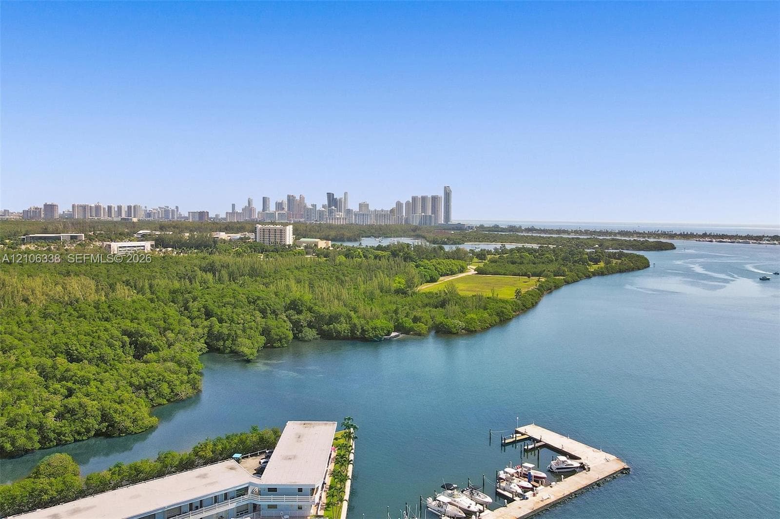 Waterfront property featuring a private boat dock, sprawling coastal greenery, and prominent skyline backdrop
