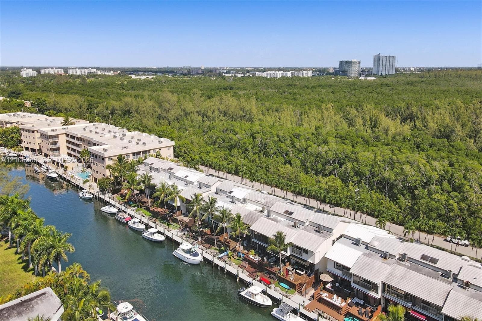 Waterfront residential complex featuring direct canal access, private boat slips, multi-level structures with terrace balconies, and mature palm landscaping