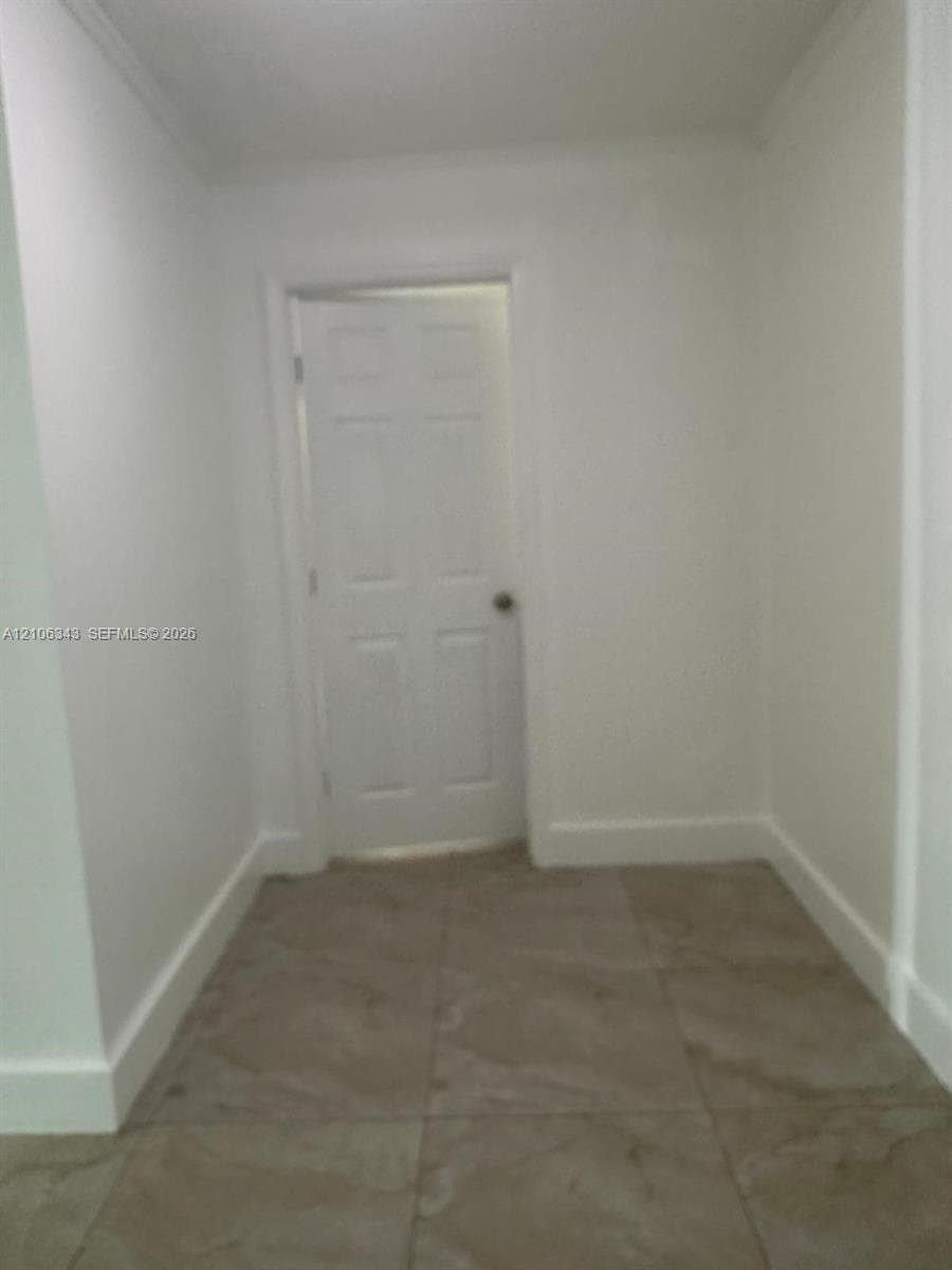 Neutral-toned floor tiles featuring large-format square composition and a six-panel interior door