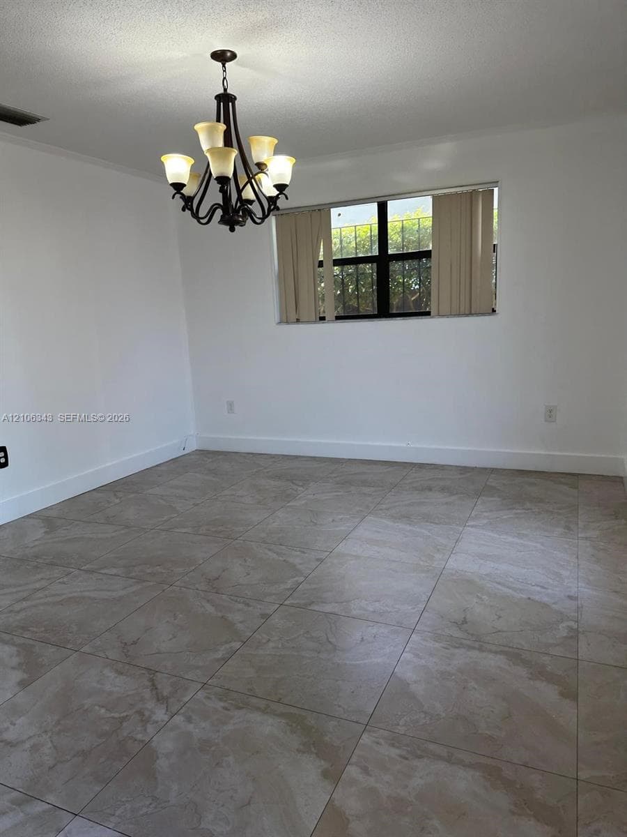 Large-format tiled flooring with neutral marbling, multi-arm metal chandelier, and black-frame window