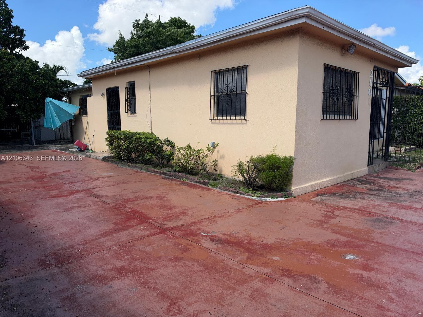 Stucco exterior featuring a concrete driveway and metal security bars on windows