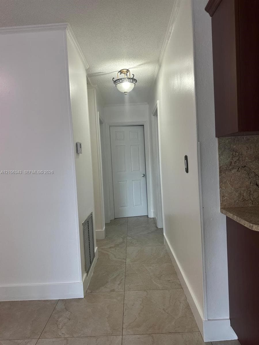 Hallway featuring neutral-toned tile flooring, semi-flush mount ceiling lighting, and six-panel interior doors