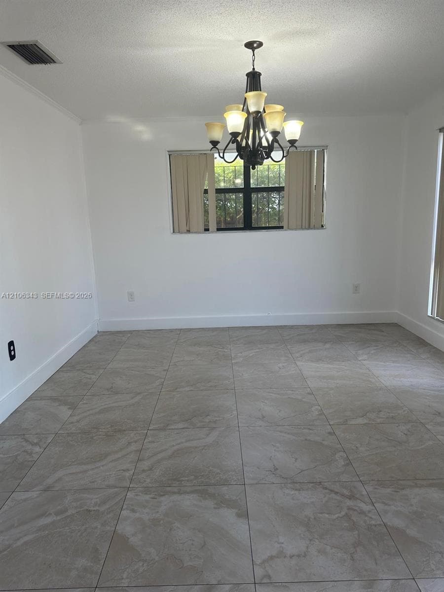 Large format neutral-toned tile flooring, multi-arm decorative chandelier, and horizontal windows with window treatments