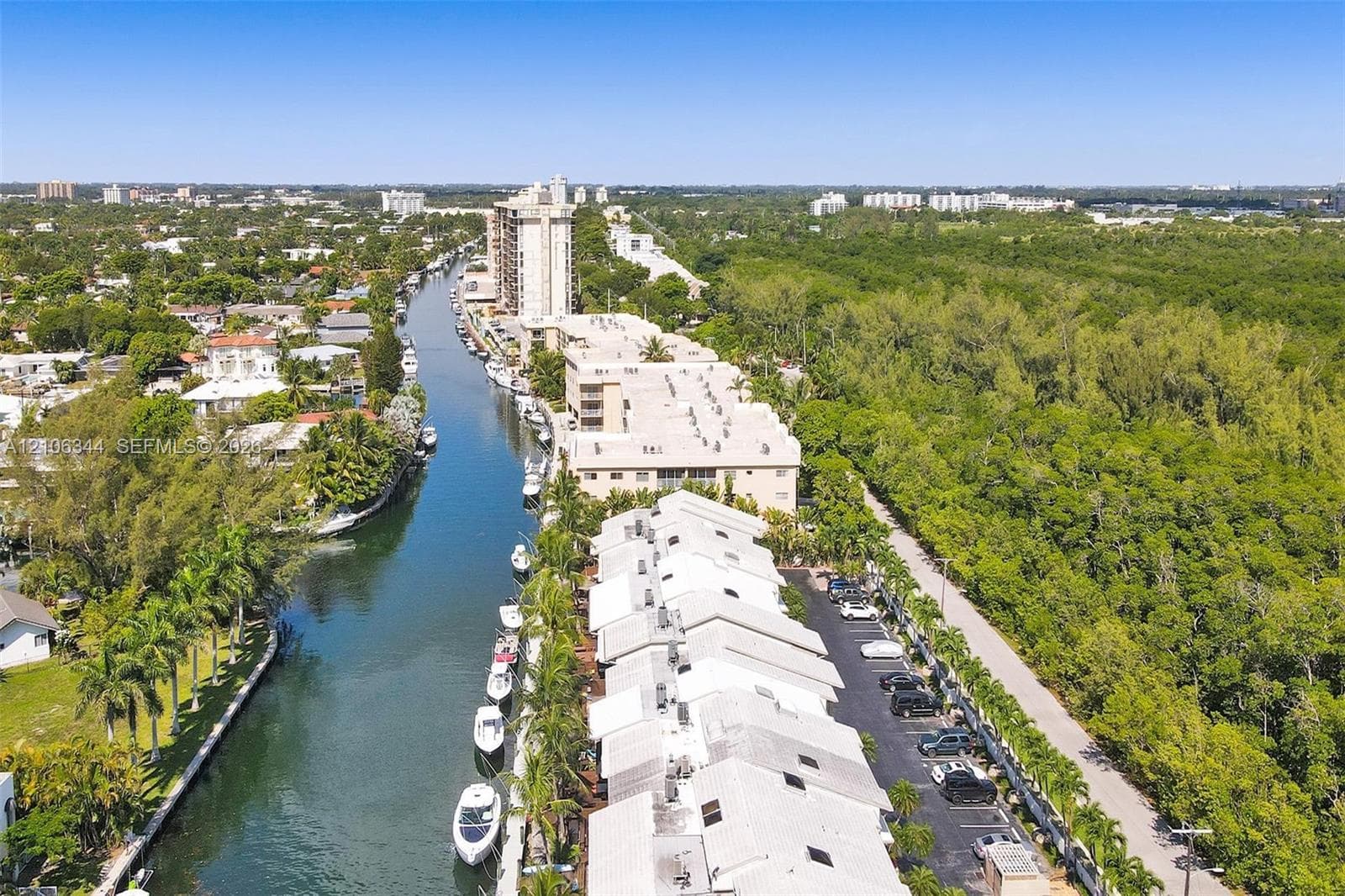 Waterfront property featuring a canal-side bulkhead with private boat slips, multi-level residential structures with pitched rooflines, and paved surface parking