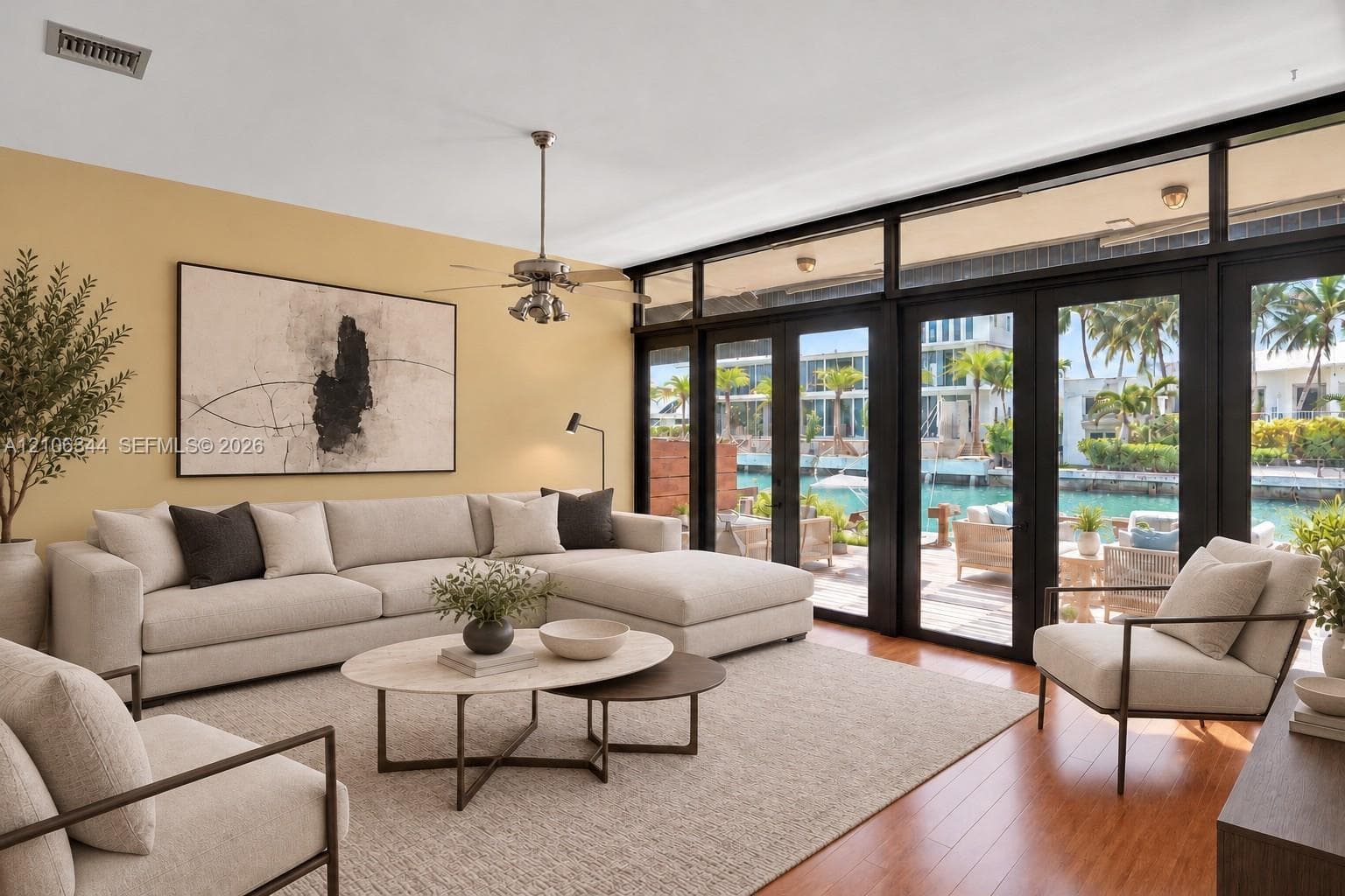 Living area featuring floor-to-ceiling glass panel doors, black metal window frames, wood-finish flooring, and a ceiling fan with integrated lighting