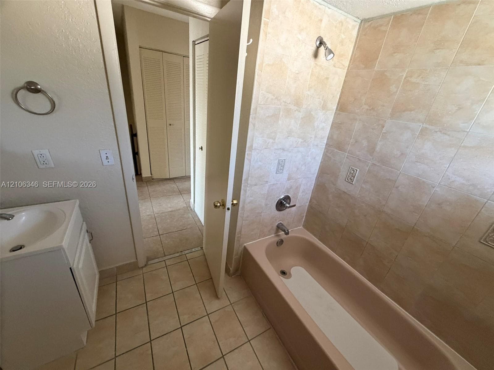 Bathroom featuring ceramic tile flooring, built-in vanity with integrated basin, tub and shower combination, and neutral ceramic wall tile surround