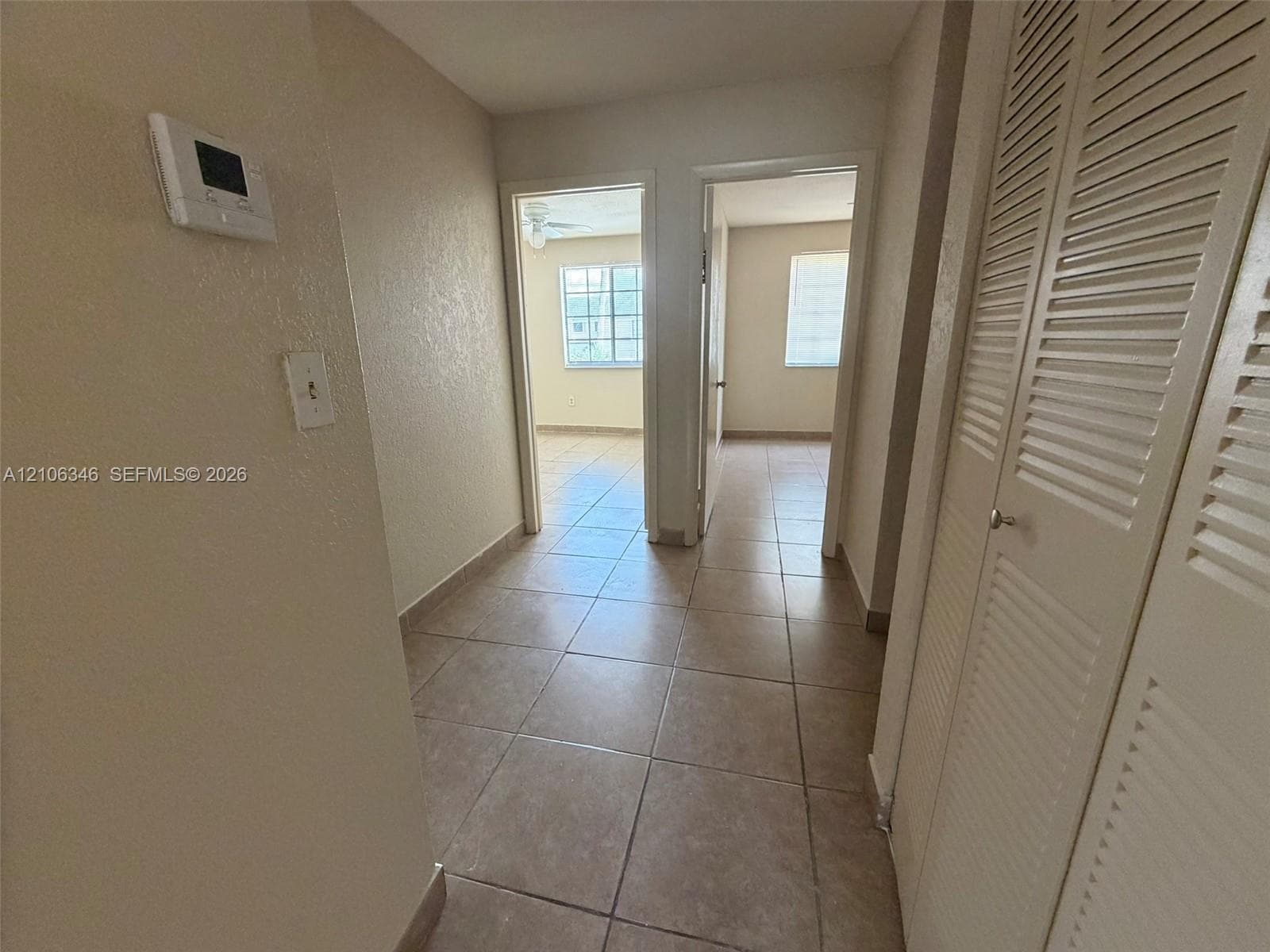 Hallway featuring ceramic tile flooring and built-in closet with louvered doors