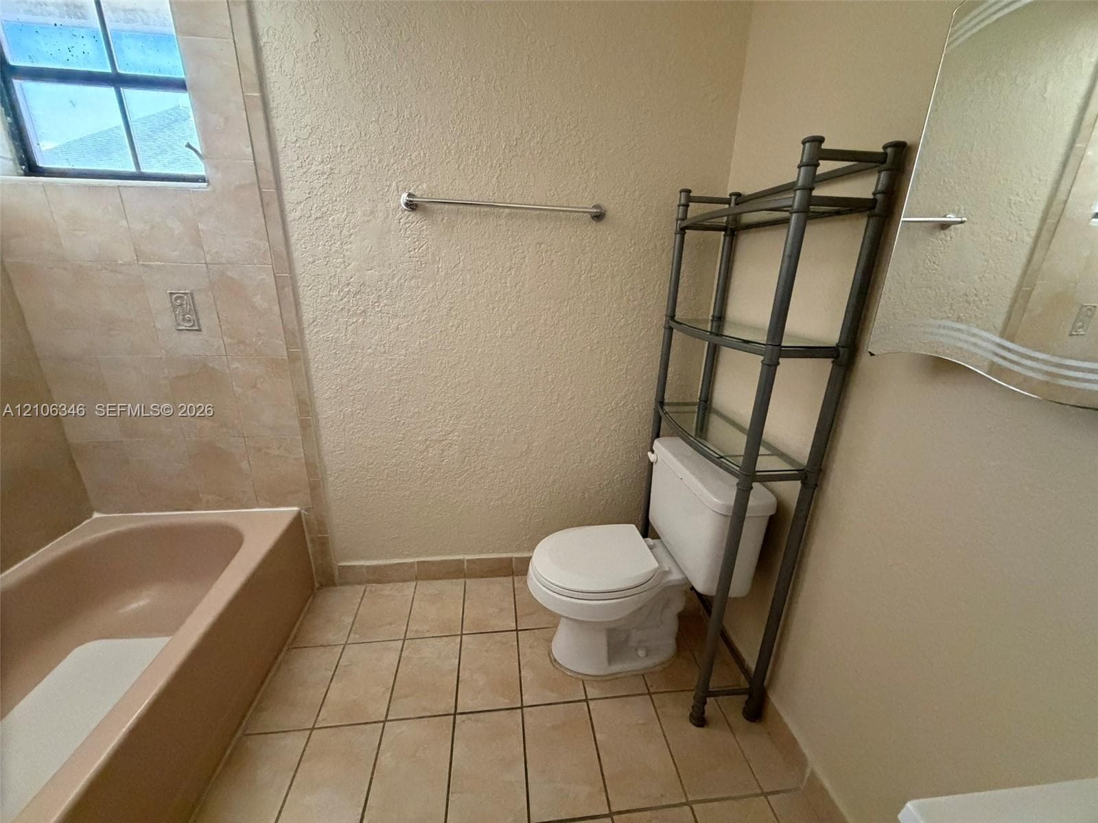 Full bathroom featuring ceramic tile flooring, a porcelain bathtub, tile-surround wall finishes, and a grid-style window