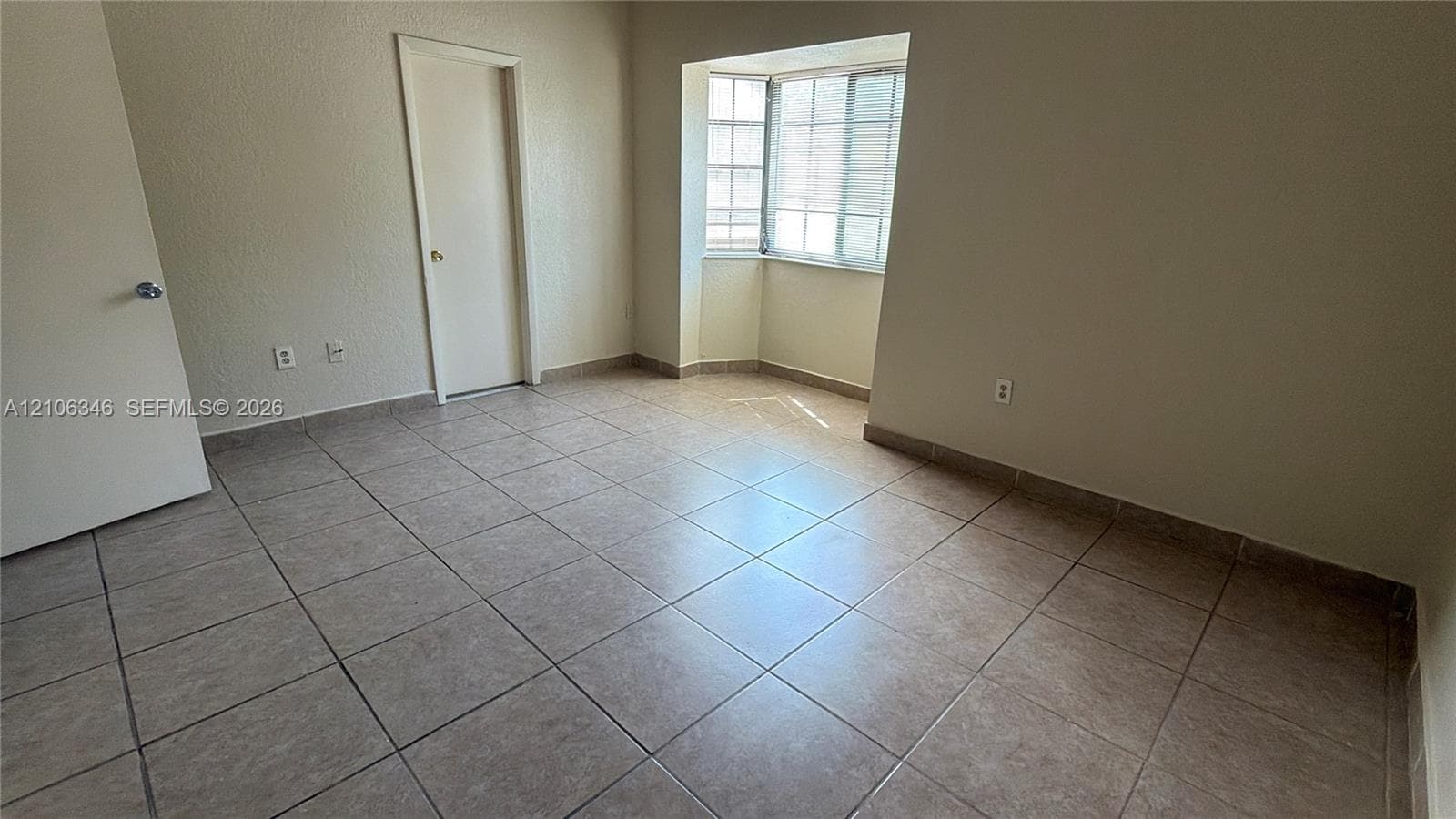 Neutral-toned tile flooring, bay window with muntin detailing, and solid core interior doors