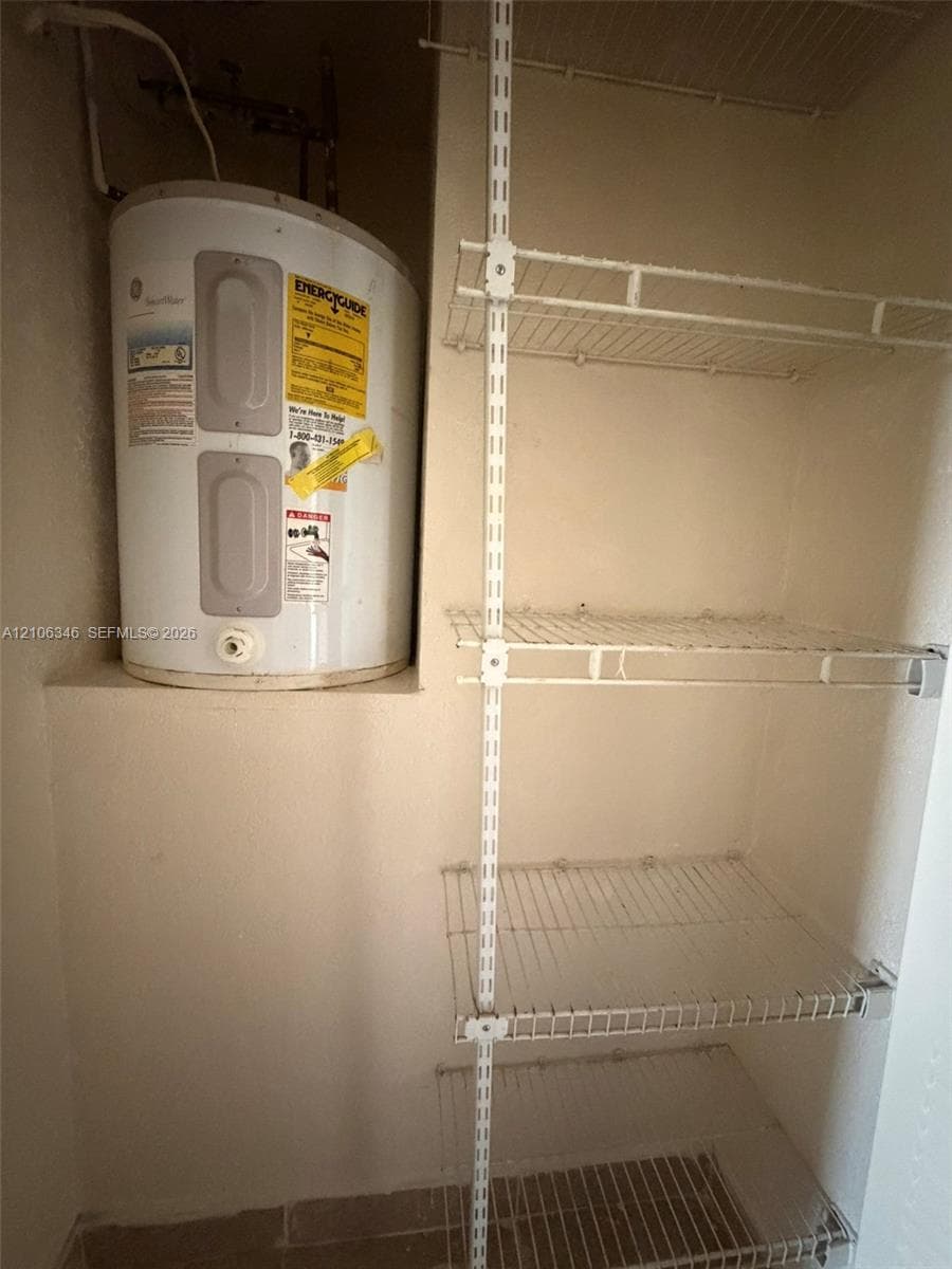 Utility area featuring a mounted water heater and adjustable wire shelving system