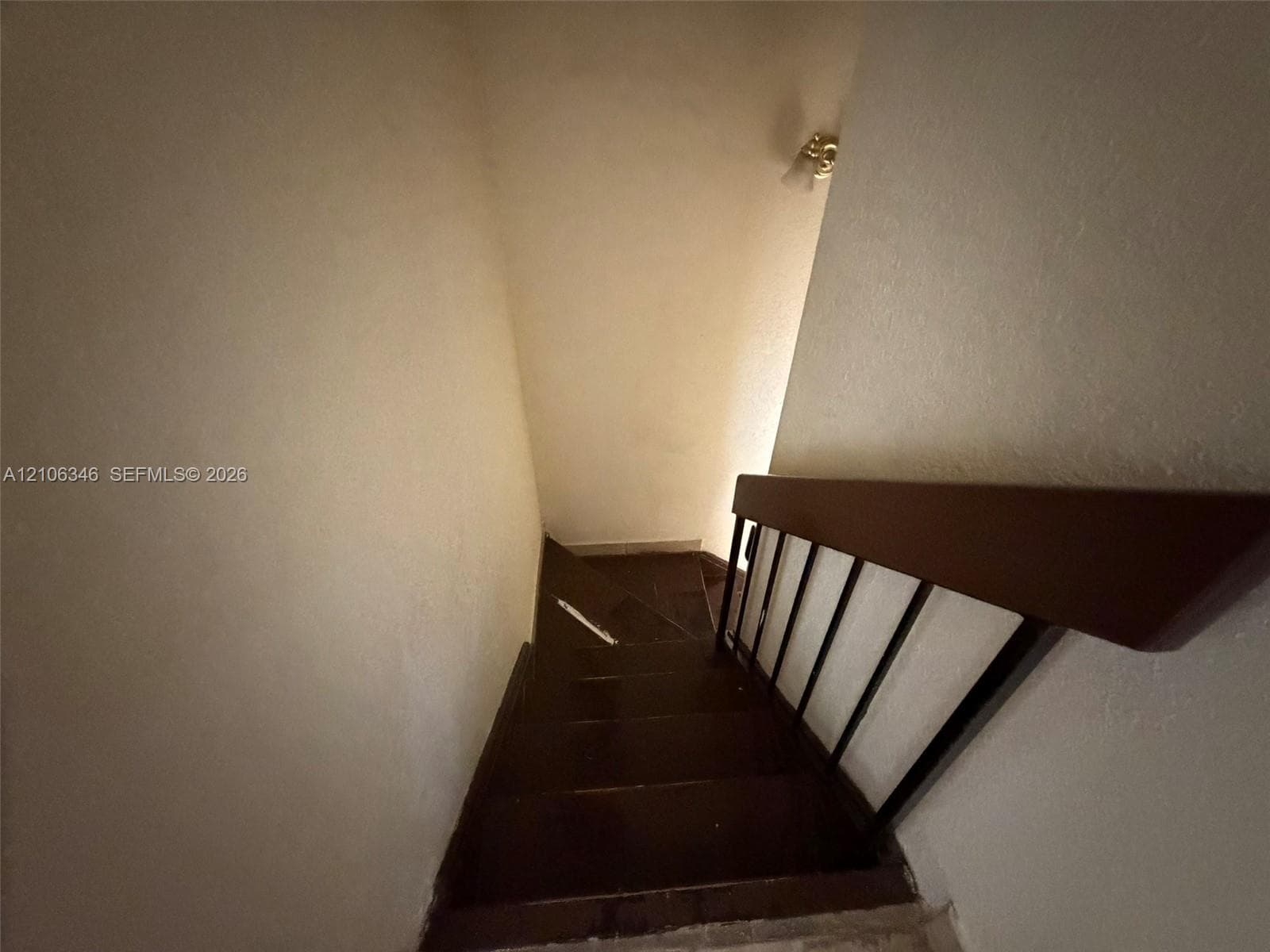 Staircase featuring dark-toned wooden treads and a metal handrail with a wooden top rail