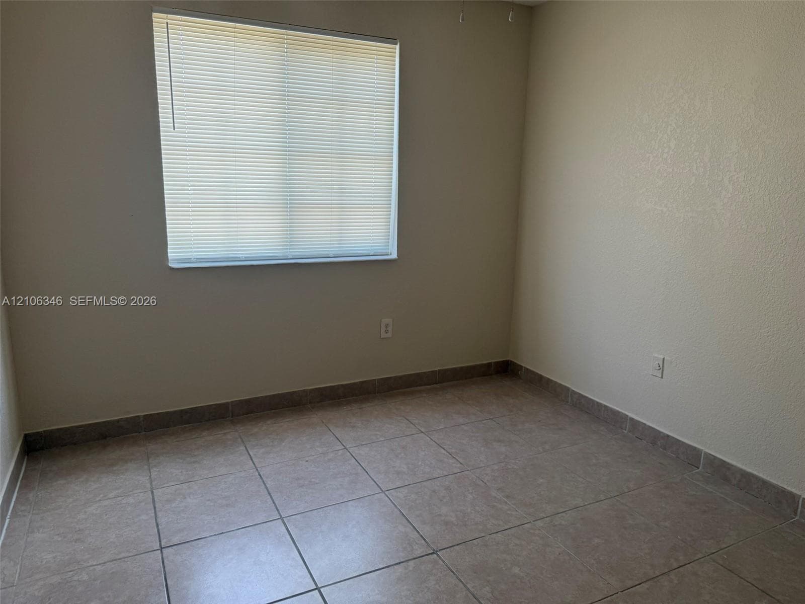 Neutral-toned walls and large-format tile flooring complemented by a window with installed horizontal blinds