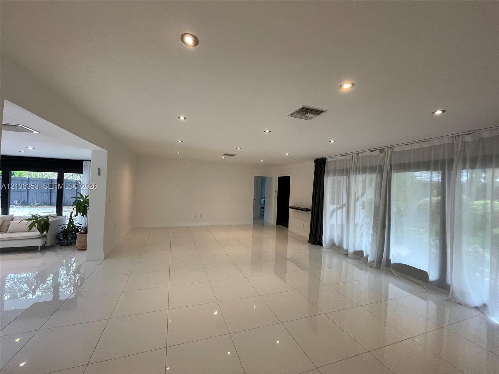 Open-concept interior featuring large-format tile flooring, recessed ceiling lighting, and floor-to-ceiling glass panel doors