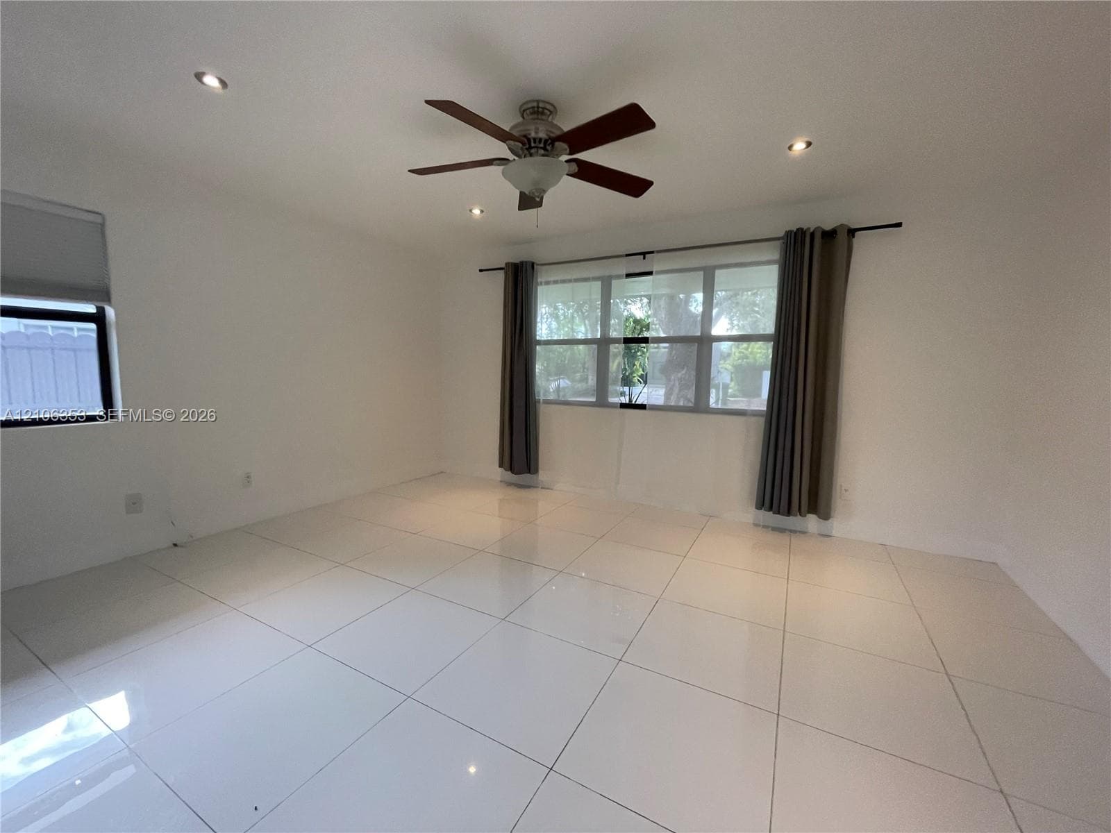 Large-format tile flooring, recessed ceiling lighting, and a multi-blade ceiling fan with integrated light fixture
