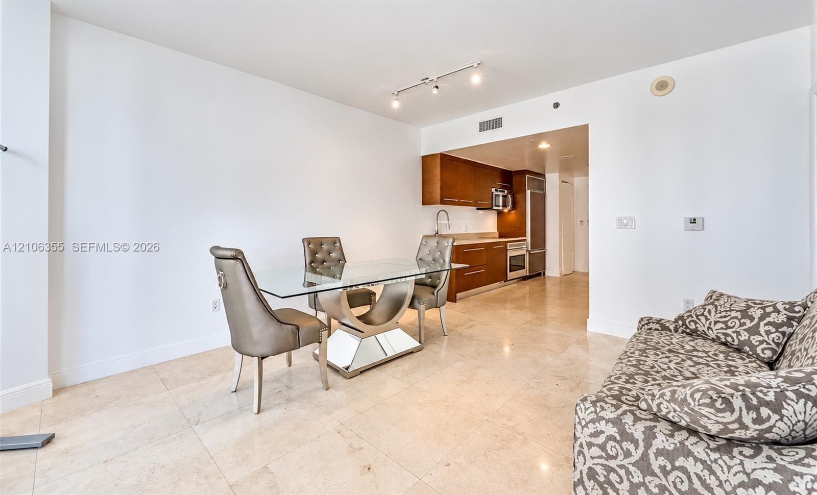 Stone flooring, track lighting, and kitchen featuring wood-finish cabinetry, built-in stainless steel appliances, and stone countertops