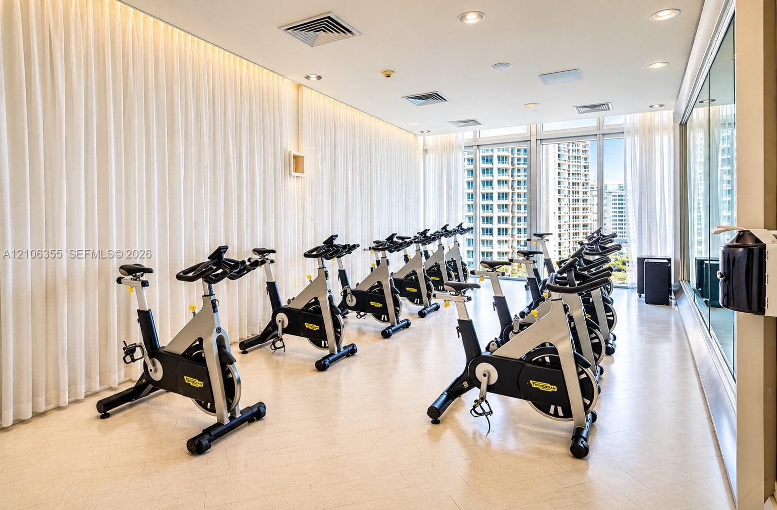 Fitness center featuring floor-to-ceiling windows, recessed lighting, expansive wall mirrors, and light-toned hard-surface flooring