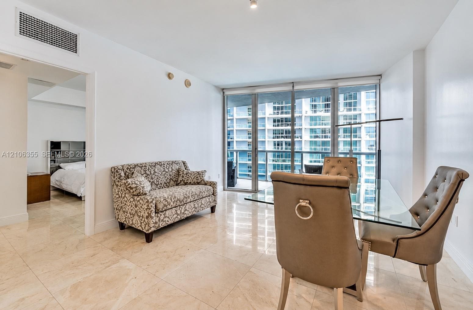 Open-concept interior featuring large-format stone flooring, floor-to-ceiling windows, and a glass balcony door