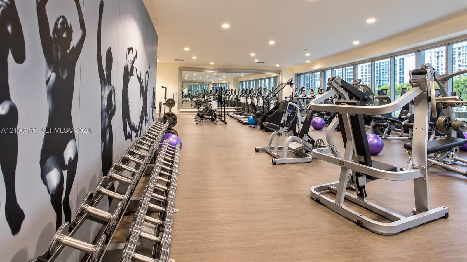 Fitness center featuring floor-to-ceiling windows, wood-finish flooring, recessed lighting, and a full-length wall mirror