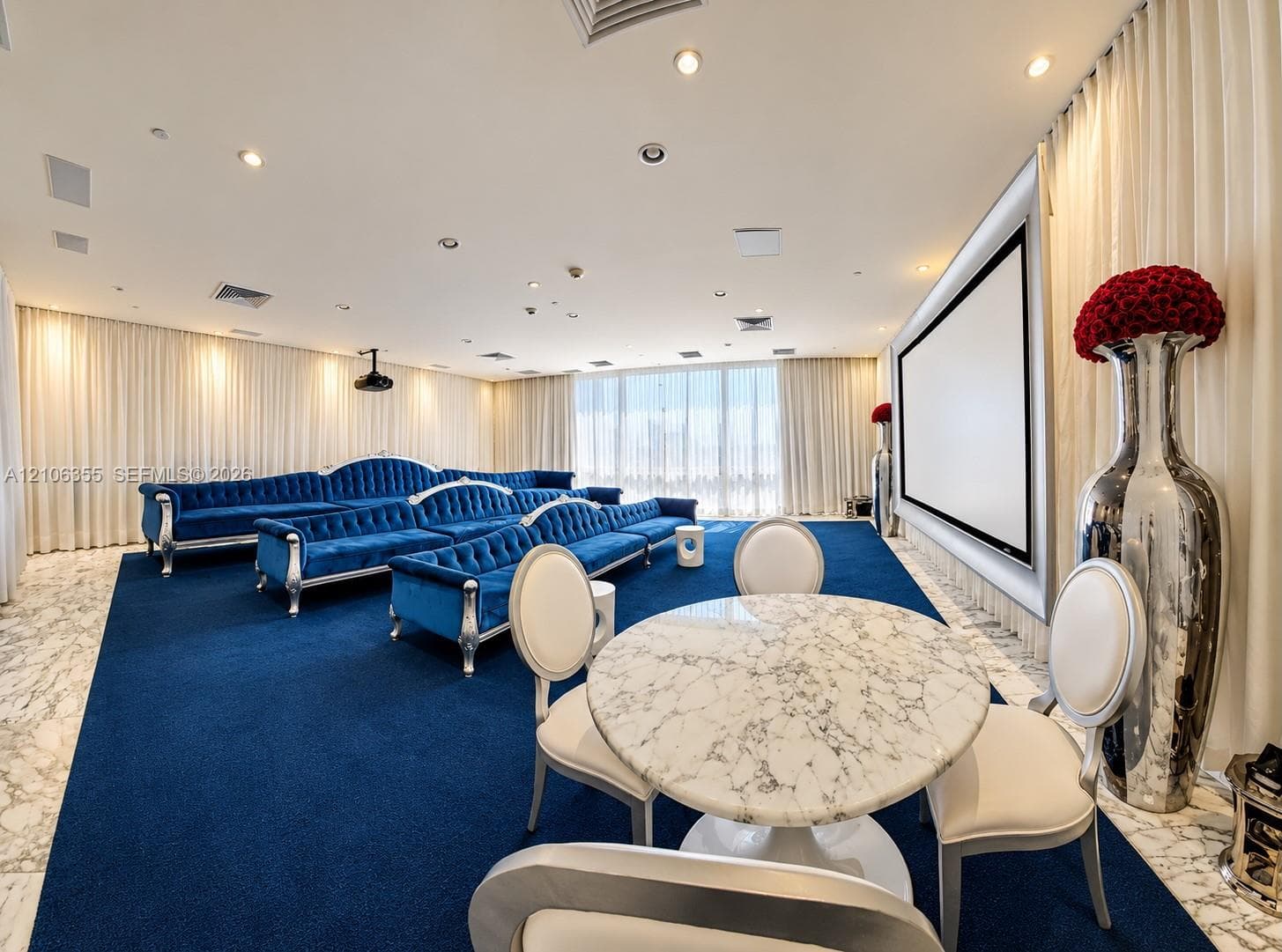 Media room featuring a wall-mounted projection screen, recessed ceiling lighting, wall-to-wall carpeting, and natural stone flooring perimeter