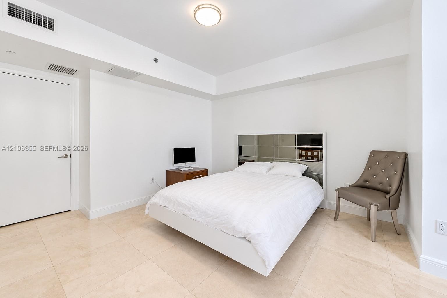 Spacious room featuring neutral stone tile flooring, high ceilings with recessed lighting, and a crisp white aesthetic